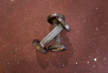İki küçük metal eski dumbbells kaba kırmızı arka plan bir spor salonu. Spor salonu ve fitness ekipmanları