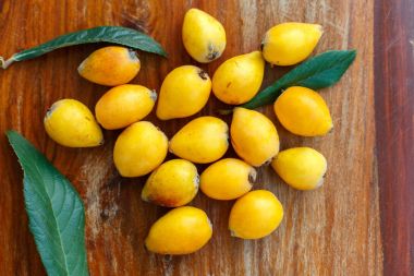 Olgun meyve muşmulası kahverengi ahşap arka plan üzerinde demet