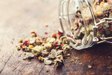 Eski ahşap bir masa üzerinde dağ bitki çayı döktü cam ja