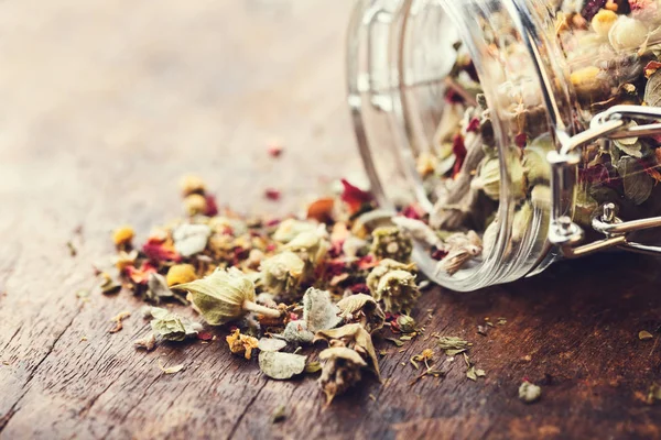 Eski ahşap bir masa üzerinde dağ bitki çayı döktü cam ja