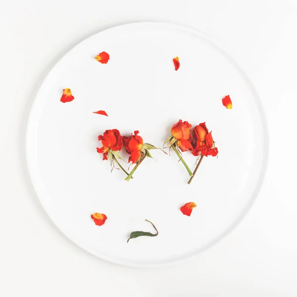 Dos imágenes de un corazón hecho de brotes de flores secas de rosas en un plato blanco — Foto de Stock