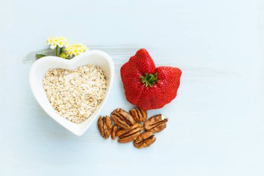 yulaf ezmesi pecans lantana çiçek kahvaltıda bir mavi ahşap zemin üzerine bir avuç bir kalp ve büyük bir çilek şeklinde bir tabak içinde