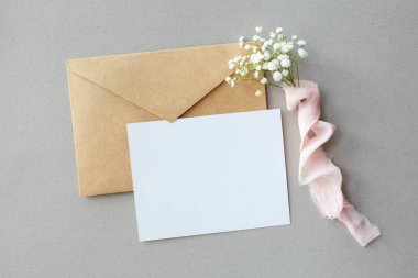 İpek kurdele, davetiye düğün, bir metni kartı ve bir zarf ile Gypsophila gri bir zemin üzerine bir mektup