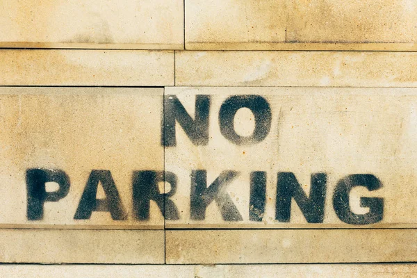 Надпись на каменной желтой стене - не парковка — стоковое фото
