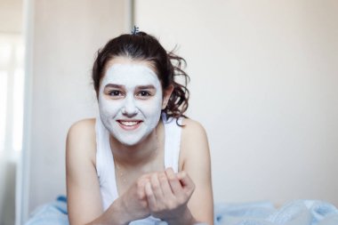 Yalan Oda, mavi renkli kozmetik maskesi yüzünde gülümser pijama giymiş genç kız ile sorun cilt, uzun saç,