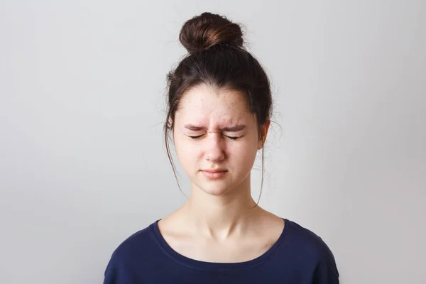 Portrait of a pimply teenage girl in a blue T-shirt on a gray background,  with eyes closed — Stock Photo, Image