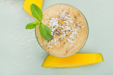 Bir bardak meyve yüzlü bir mavi ahşap tablo adet mango ile Hindistan cevizi talaşı ve nane fışkın. Sağlıklı beslenme, üstten görünüm, yakın çekim kavramı.