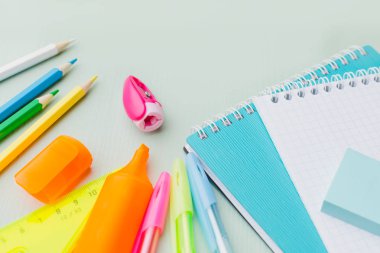 Ahşap bir mavi masa, bir not defteri, renkli kalem, cetvel, marker, planya, metin için yer üzerinde çeşitli ileti örneği yığını. Çocuklar okul için hazırlık kavramı.