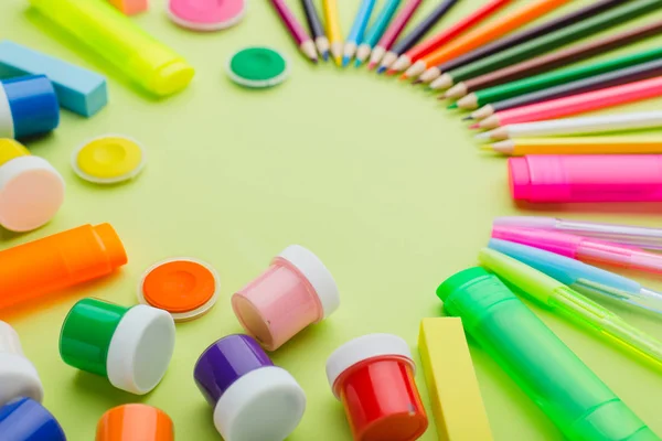 Lots of stationery on a green background, multi-colored paints, pencils, markers, eraser, ruler, sharpener, scissors, stapler. The concept of preparing children back to school. Copy space. — Stock Photo, Image