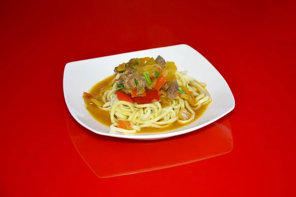 Kafeteryadaki fotoğrafta yemek, kırmızı arka planda Uighur eriştesi var..