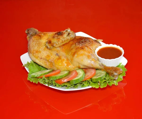 食堂の写真は赤を背景に野菜とソースをかけた皿の上に盛り付けられた鶏の唐揚げ — ストック写真