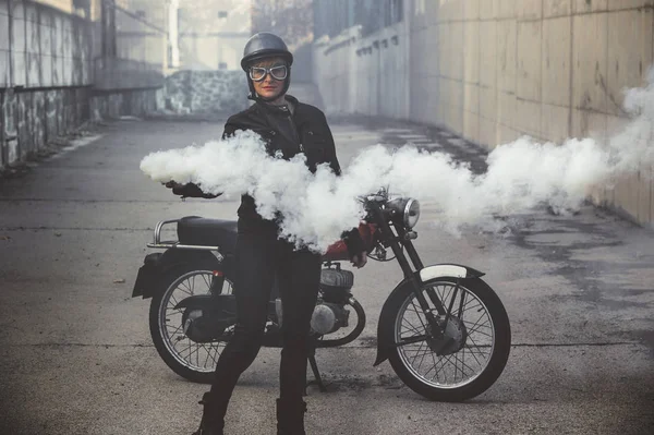 Femme moto dans la rue tenant une fusée éclairante de fumée — Photo de stock