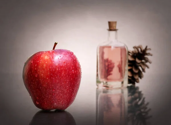 赤熟したリンゴとまだ生活 ヴィンテージのガラス瓶と低キーの背景に松のコーンに不可欠なアロマオイル 驚くべき反射 選択的かつソフトフォーカス — ストック写真