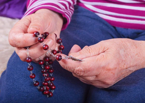 Handen van een oudere vrouw met een rozenkrans — Stockfoto