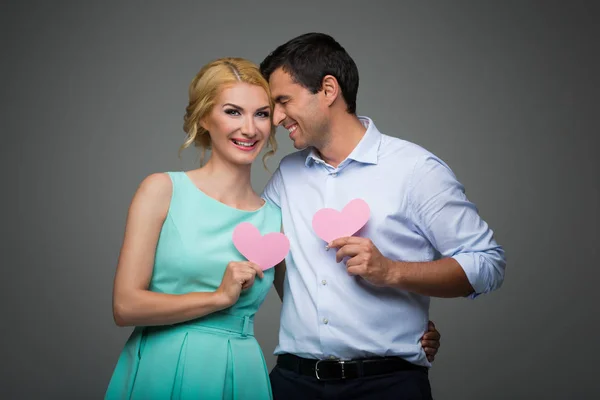 Hermosa pareja sosteniendo corazones rosados — Foto de Stock