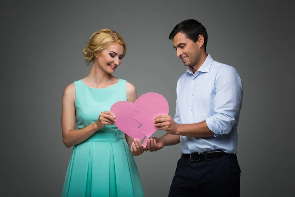 Beautiful couple holding pink broken heart — Stock Photo, Image