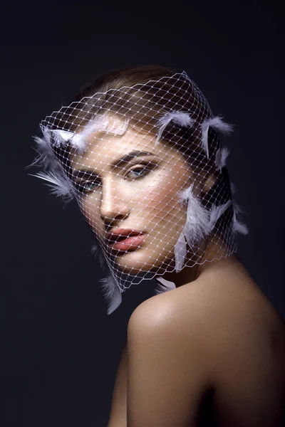 Beautiful girl in veil with feathers