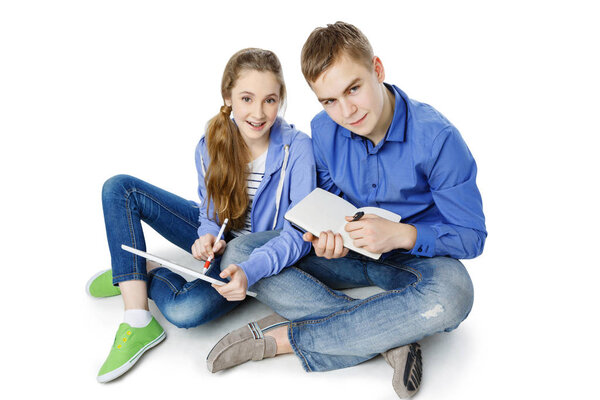 Teen age boy and girl with tablet and notebook