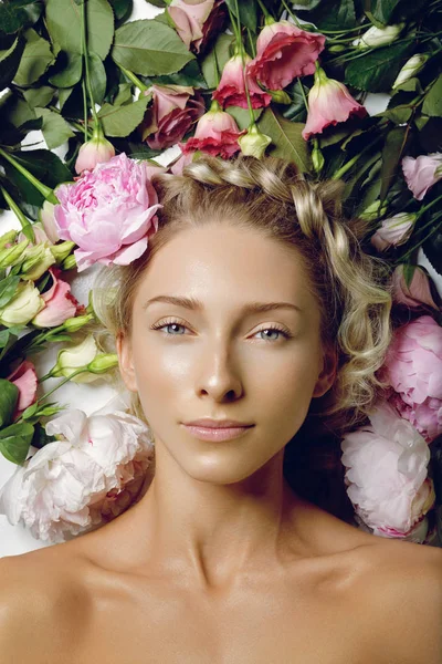 Hermosa chica acostada en flores — Foto de Stock