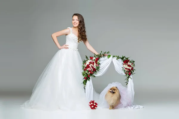 Ženské nevěsty s nevěstou psa pod květiny oblouk — Stock fotografie
