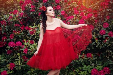 güzel saç modeli ve parlak makyaj ayakta ormangülü çiçek bahçe içinde güzel genç kadın. Açık yaz vurdu. kopya alanı.