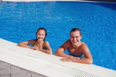 boy and girl having fun in swimming pool clipart