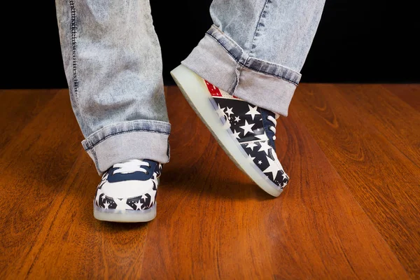 Vrouw jeans en sneaker schoenen op houten vloer — Stockfoto