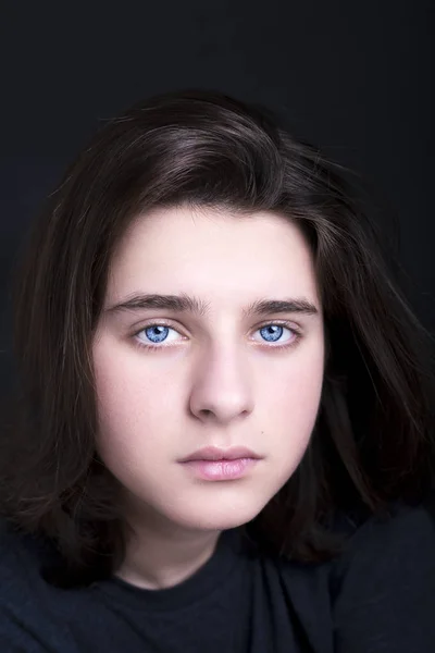 Un retrato de un guapo ojos azules adolescente sobre fondo oscuro — Foto de Stock