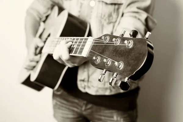 Ο άνθρωπος παίζει κιθάρα στο στούντιο φορώντας τζιν μπουφάν. — Φωτογραφία Αρχείου
