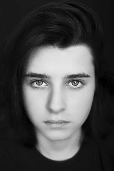 Un retrato de un guapo adolescente sobre un fondo oscuro. Monocromo —  Fotos de Stock