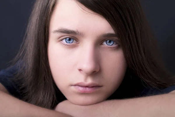 Um retrato de um belo adolescente de olhos azuis no fundo escuro — Fotografia de Stock