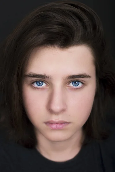 Portrait d'un bel adolescent aux yeux bleus sur fond sombre — Photo