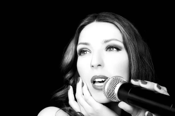 Portrait of beautiful singing woman on black background, close up — Stock Photo, Image