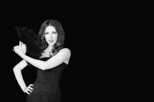 Beautiful woman in black dress holding fan of  feathers on dark studio background — Stock Photo, Image