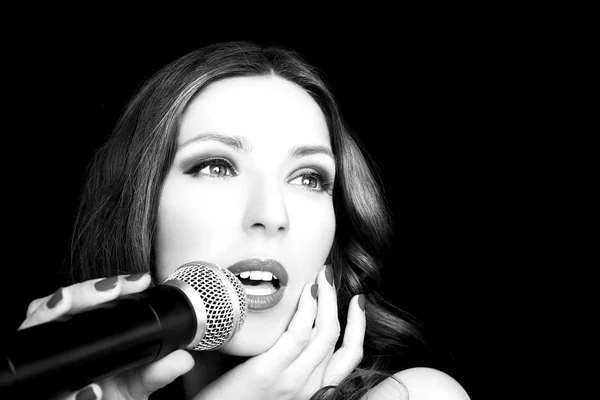 Portrait of beautiful singing woman on black background, close up — Stock Photo, Image