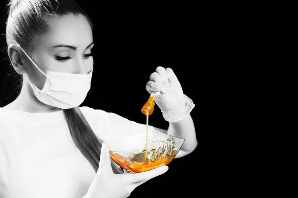 Woman with sugar hair removing paste on black background