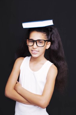 Sevimli kız gözlük ve kafasına kitap okuyor 