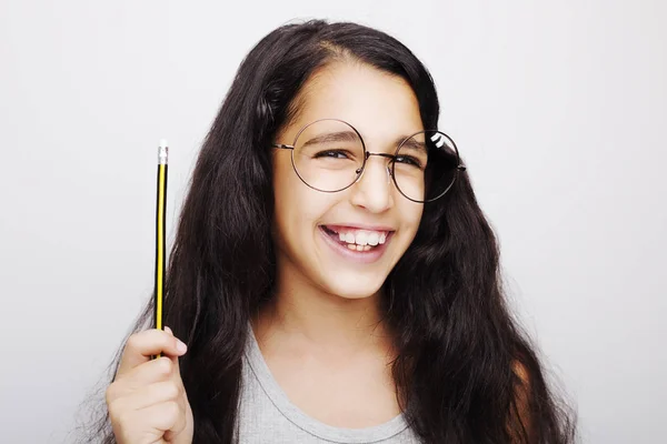 A beautiful African kid girl in glasses holding pencil in hand — Stock Photo, Image