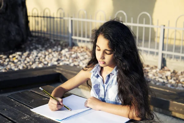 Güzel bir kız kalp parkta çizer.