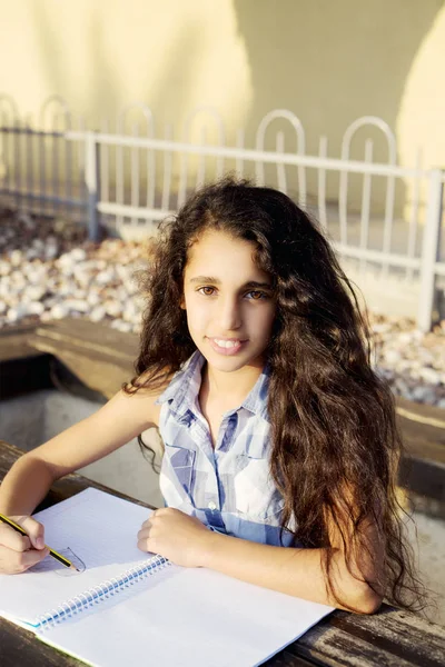 Güzel bir kız kalp parkta çizer.