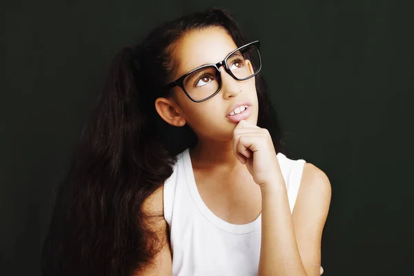 Menina adorável estudando com óculos em fundo preto — Fotografia de Stock