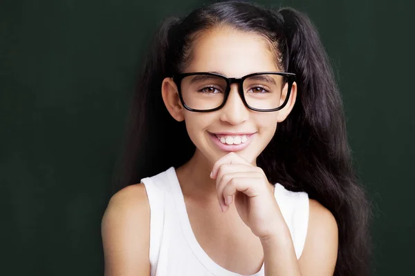 Menina adorável estudando com óculos no fundo escuro — Fotografia de Stock