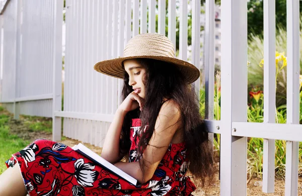 Adorável menina em vestido e chapéu livro de leitura no parque de verão . — Fotografia de Stock