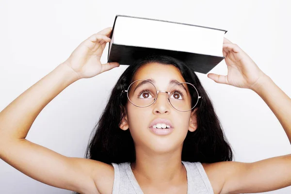 Entzückendes Mädchen mit Brille und Buch auf dem Kopf — Stockfoto