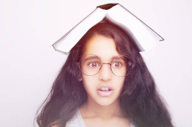 Sevimli kız gözlük ve kafasına kitap okuyor 