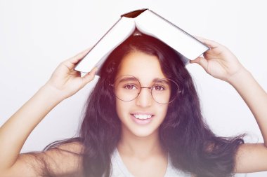 Sevimli kız gözlük ve kafasına kitap okuyor 