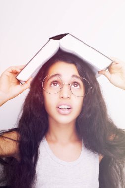 Sevimli kız gözlük ve kafasına kitap okuyor
