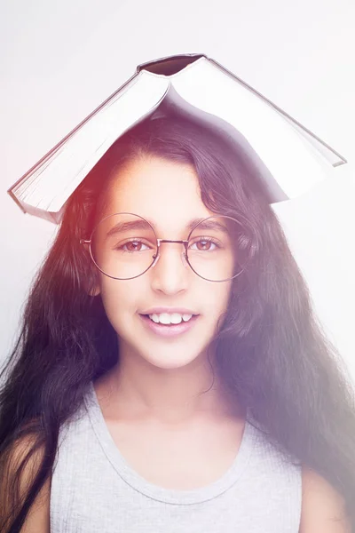 Rozkošný dívka studovat brýle a knihu na hlavu — Stock fotografie