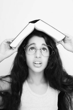 Sevimli kız gözlük ve kafasına kitap okuyor 