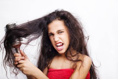 Üzerinde kızın portresi olan saç bakım konsepti. Asi, karmaşık saçlarını tarıyor. Beyazların üzerinde izole edilmiş.